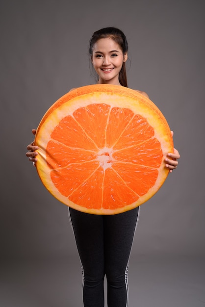 Belle jeune femme asiatique tenant grosse orange