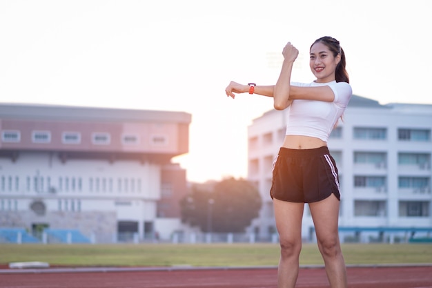 Une belle jeune femme asiatique en tenue de sport faisant des étirements avant de s'entraîner en plein air dans le parc le matin pour adopter un mode de vie sain. Jeune femme en bonne santé se réchauffant à l'extérieur