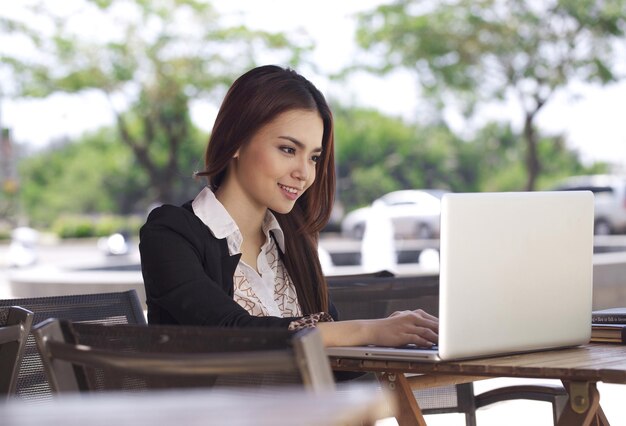 Belle jeune femme asiatique travaillant sur un ordinateur portable dans un café