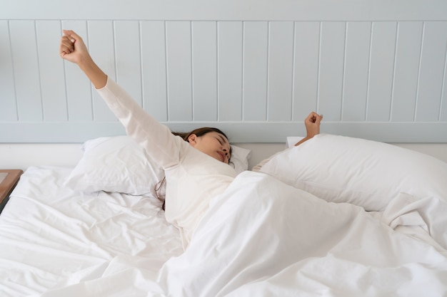 Belle jeune femme asiatique trop paresseuse pour sortir du lit le matin.