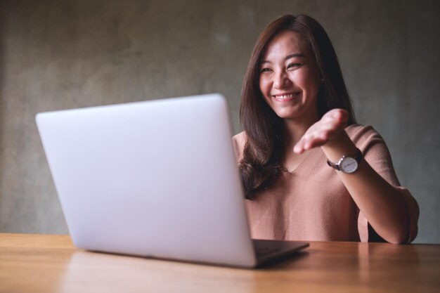 Une belle jeune femme asiatique utilisant un ordinateur portable pour un appel vidéo et travaillant en ligne à la maison