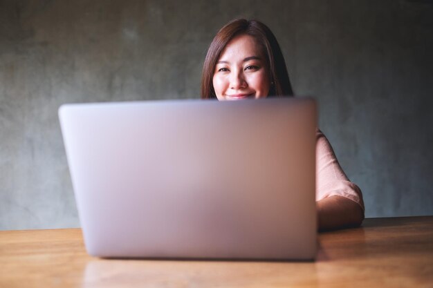 Une belle jeune femme asiatique utilisant et travaillant sur un ordinateur portable