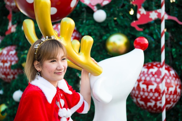 Belle jeune femme asiatique en vêtements de Père Noël à l'extérieurThaïlandaisEnvoyé du bonheur pour les enfantsJoyeux NoëlBienvenue en hiverFond de Noël décoré