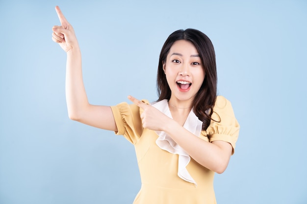 Belle jeune femme asiatique vêtue d'une robe jaune sur fond noir bleu