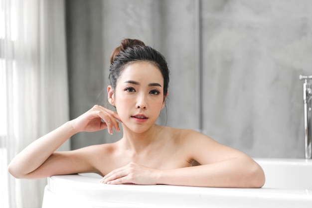 Belle jeune femme Asie profiter de se détendre en prenant un bain avec de la mousse à bulles dans la baignoire à la salle de bain