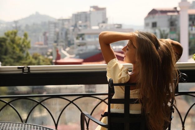 Belle jeune femme assise sur le balcon vue arrière Espace pour le texte