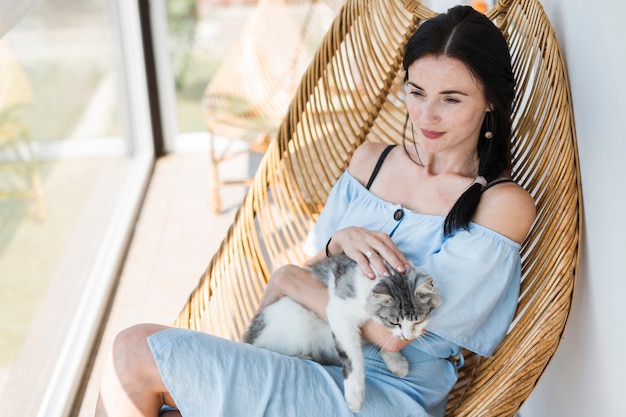 Belle jeune femme assise sur une chaise avec son chat mignon