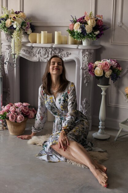 Belle jeune femme assise dans une pièce parmi les fleurs