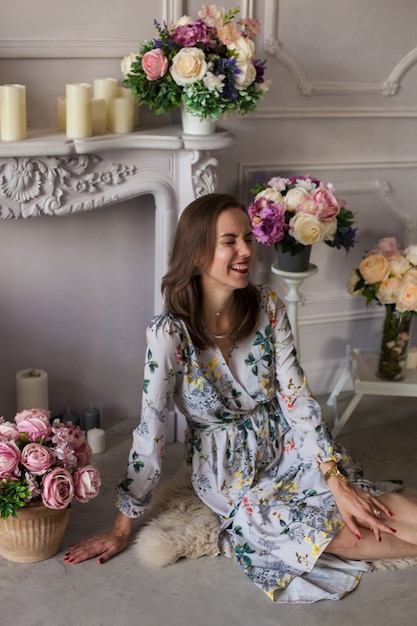 Belle jeune femme assise dans une pièce parmi les fleurs