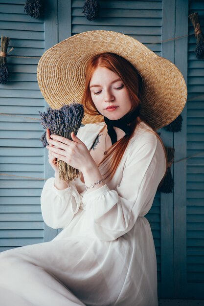 Belle jeune femme assise à la lavande contre le mur bleu.