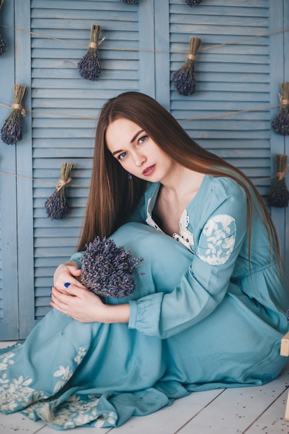 Belle jeune femme assise à la lavande contre le mur bleu.