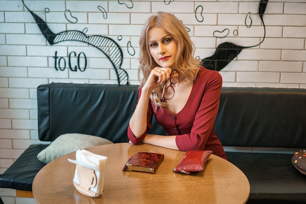 Belle jeune femme assise à une table avec un cahier et un téléphone.