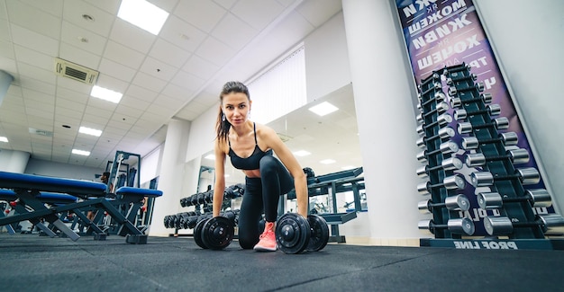 Belle jeune femme athlétique faisant de l'exercice à la salle de gym