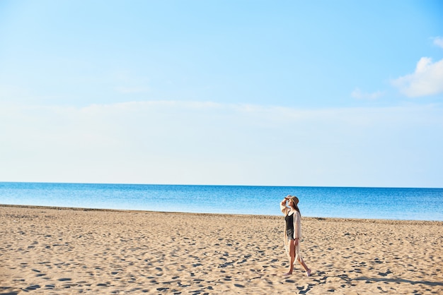 Belle jeune femme au chapeau de paille sur la plage