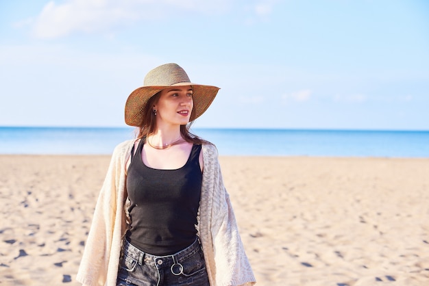 Belle jeune femme au chapeau de paille sur la plage
