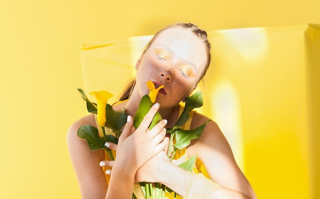 Belle jeune femme au visage de taches de rousseur vêtue d'une robe jaune près de l'arrière-plan avec les ombres de l'après-midi