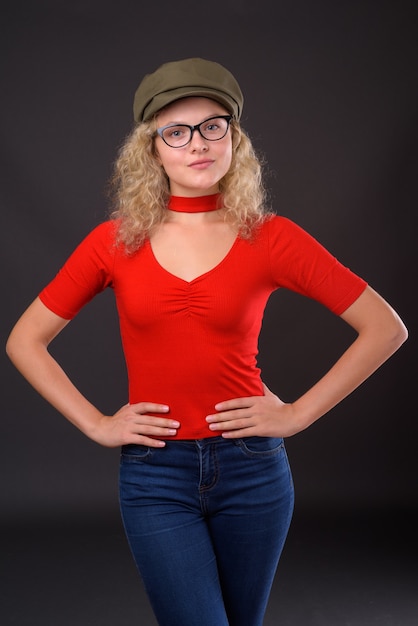 Belle jeune femme aux cheveux blonds bouclés contre gris