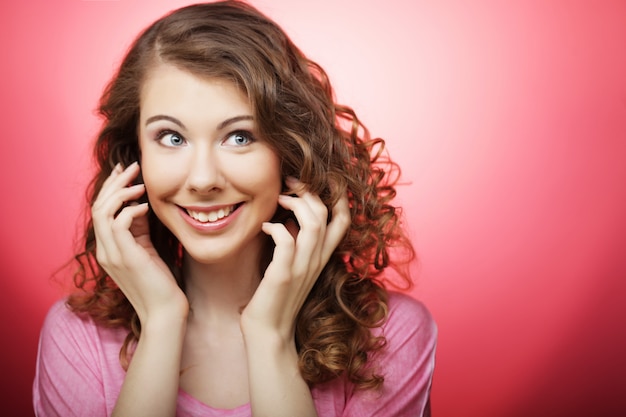 Belle jeune femme aux cheveux bouclés sur fond rose