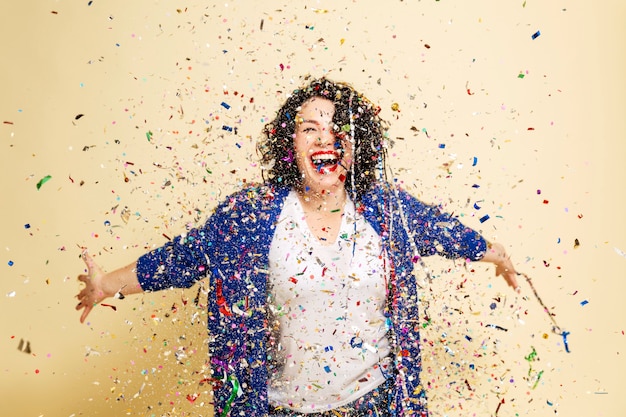 Photo belle jeune femme aux cheveux bouclés parsemée de rires de confettis.