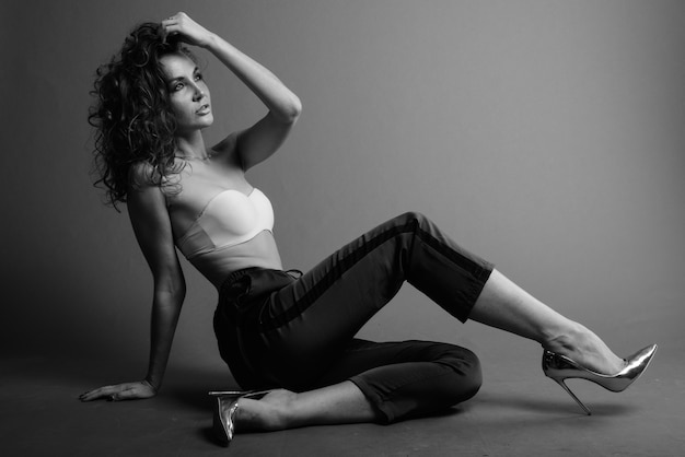 Belle jeune femme aux cheveux bouclés posant en noir et blanc