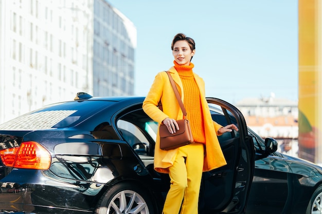 Belle jeune femme aux cheveux courts conduit une voiture dans la ville