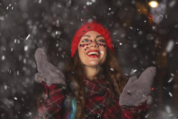 Belle jeune femme aux cheveux longs appréciant le temps neigeux à la foire de Noël