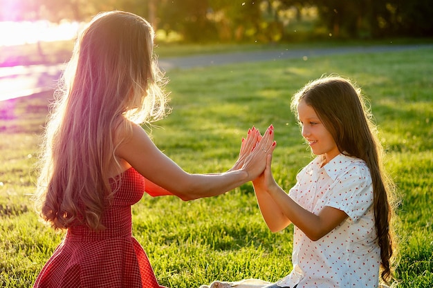 Belle et jeune femme aux cheveux longs jouant avec sa fille un jour d'été dans le parc