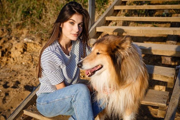 Belle jeune femme aux cheveux longs marchant avec chien colley. À l'extérieur dans le parc. près de la mer, été beatch