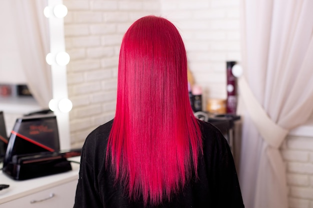 Belle jeune femme aux cheveux roses sur fond de salon de coiffure