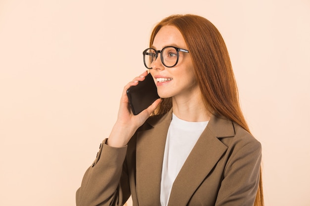 Belle jeune femme aux cheveux rouges dans une veste sur fond beige