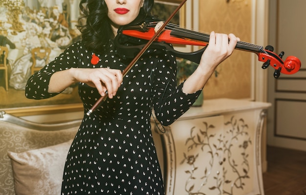 Belle jeune femme aux lèvres rouges jouant du violon