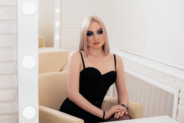 Belle jeune femme aux longs cheveux blonds en bonne santé regardant le miroir dans un salon de coiffure