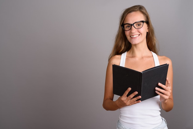 Belle jeune femme aux longs cheveux blonds sur fond gris