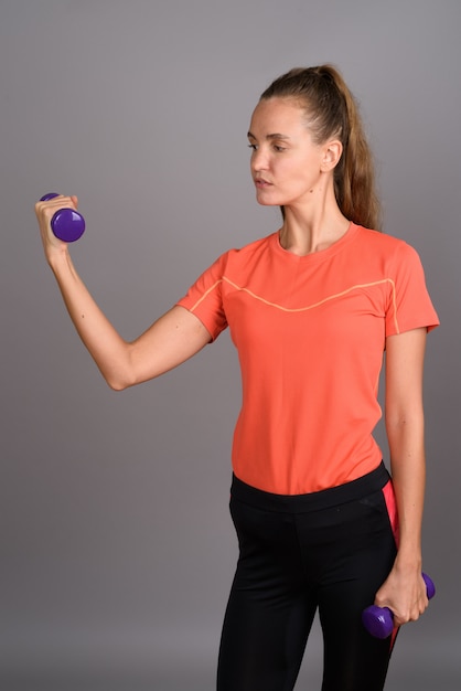 Belle jeune femme aux longs cheveux blonds prêt pour la gym sur fond gris