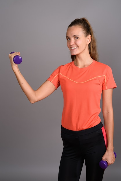 Belle jeune femme aux longs cheveux blonds prêt pour la gym sur fond gris