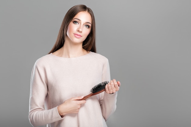 Belle jeune femme aux longs cheveux naturels lisses tient la brosse à cheveux. espace de copie