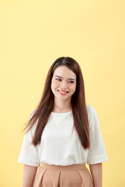 Belle jeune femme aux longs cheveux noirs posant sur fond jaune