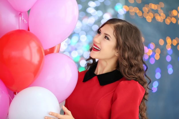 Belle jeune femme avec des ballons à air sur fond de lumières floues