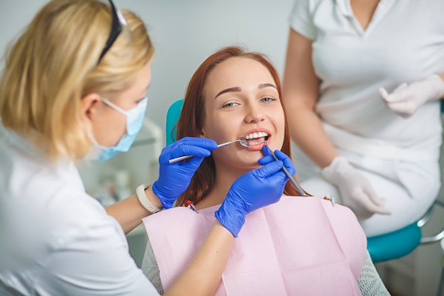 Belle jeune femme avec de belles dents blanches, assis sur un fauteuil dentaire.