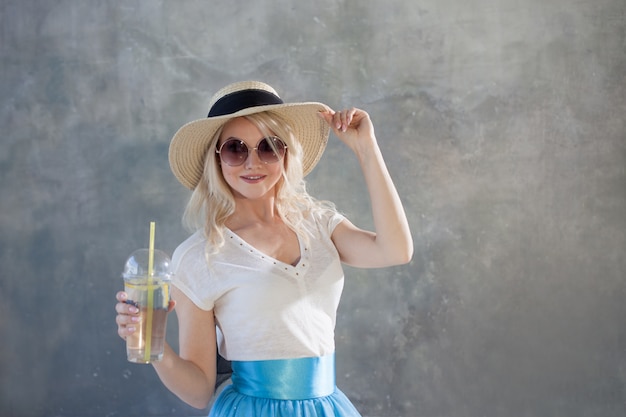 Belle jeune femme blonde au chapeau de paille. Lunettes de soleil style été.