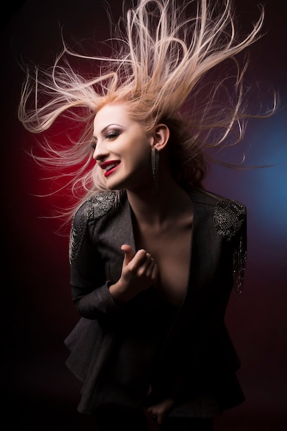 Belle jeune femme blonde aux cheveux en mouvement au studio