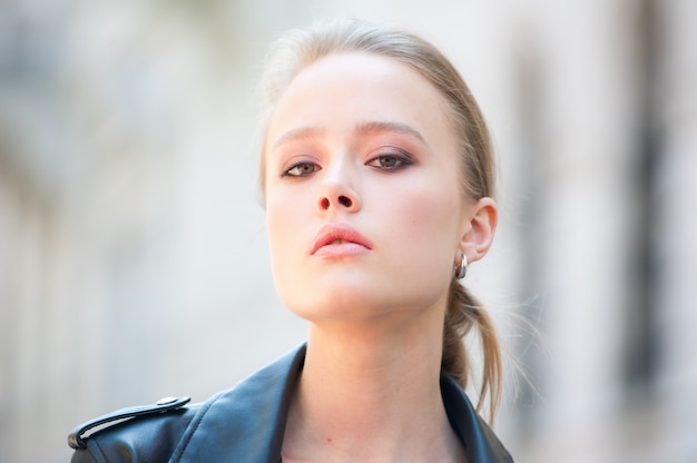 Belle jeune femme blonde dans une veste en cuir en plein air