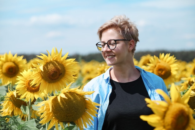 Belle jeune femme blonde debout dans le champ de tournesol