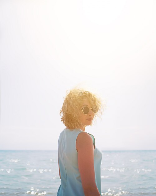 Belle jeune femme blonde à lunettes de soleil à la plage sur un fond de mer