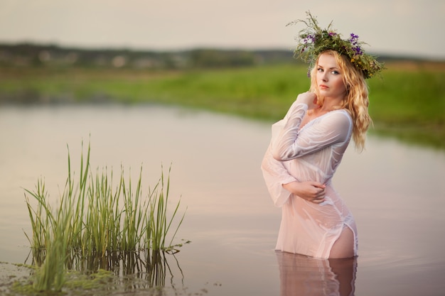 Belle jeune femme blonde en mini robe blanche et couronne de fleurs