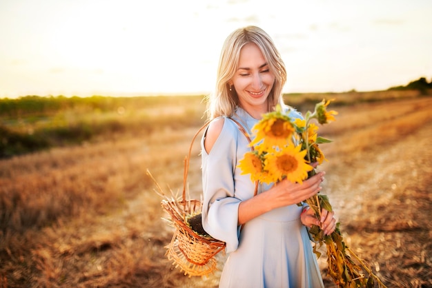 Belle jeune femme blonde positive dans une robe d'été légère se promène sur le terrain