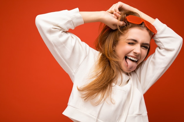 Belle jeune femme blonde ravie isolée sur fond coloré portant du blanc décontracté