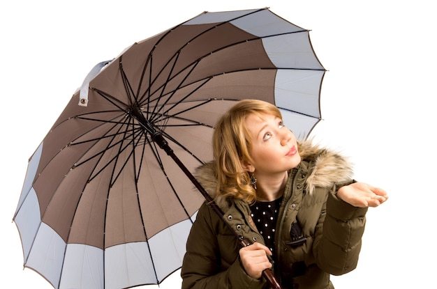 Belle jeune femme blonde vêtue d'une veste d'hiver garnie de fourrure et tenant un parapluie