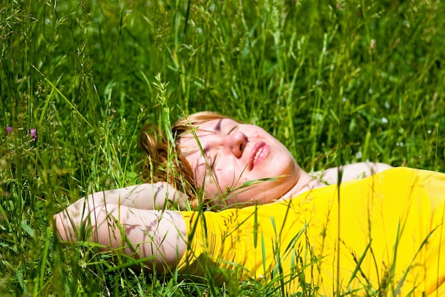 Belle jeune femme en bonne santé allongée et relaxante sur le sujet de l'herbe verte est floue