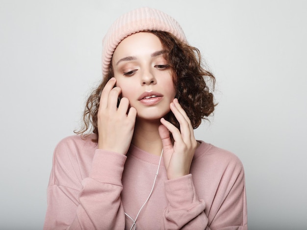 Belle jeune femme bouclée dans des écouteurs écoutant de la musique en souriant les yeux fermés